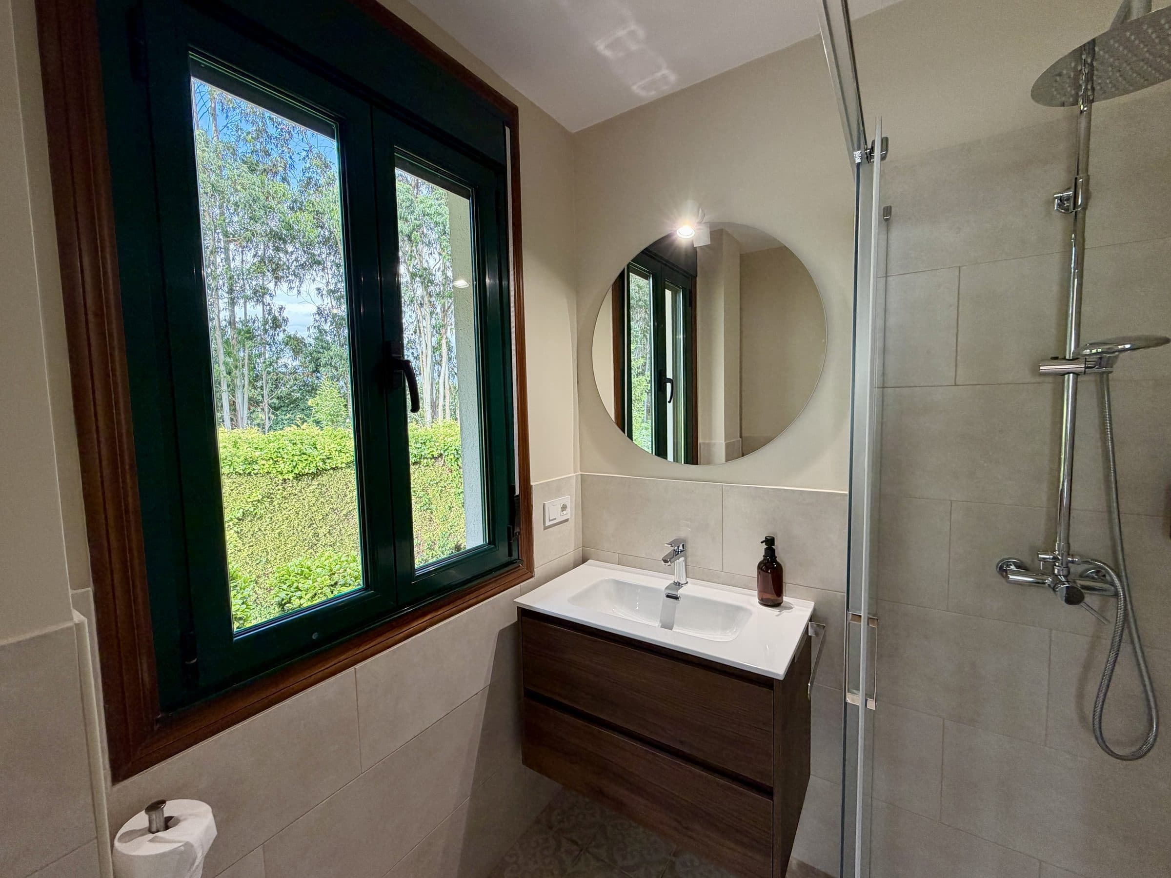 Baño de Finca La Oliva con espejo redondo, ducha y ventana al jardín