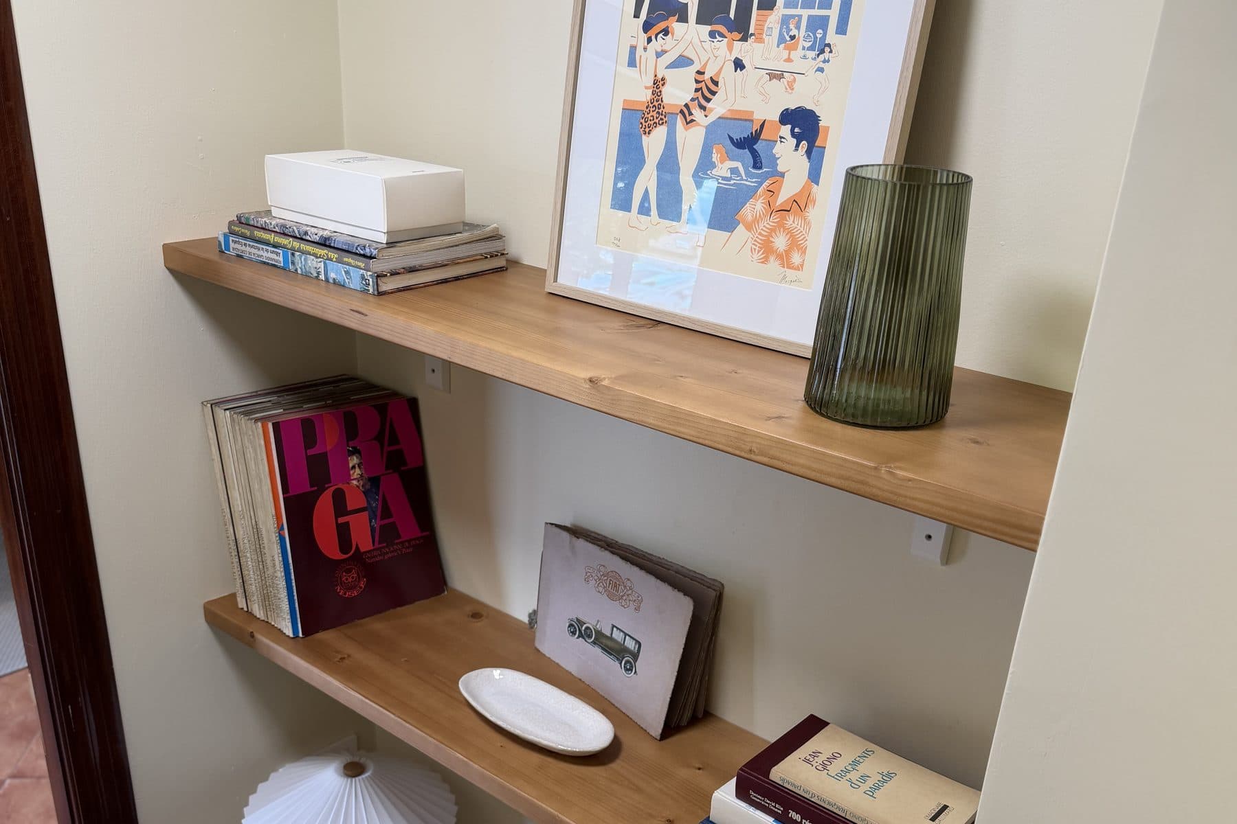 Estantería con libros, una lámina enmarcada y objetos decorativos