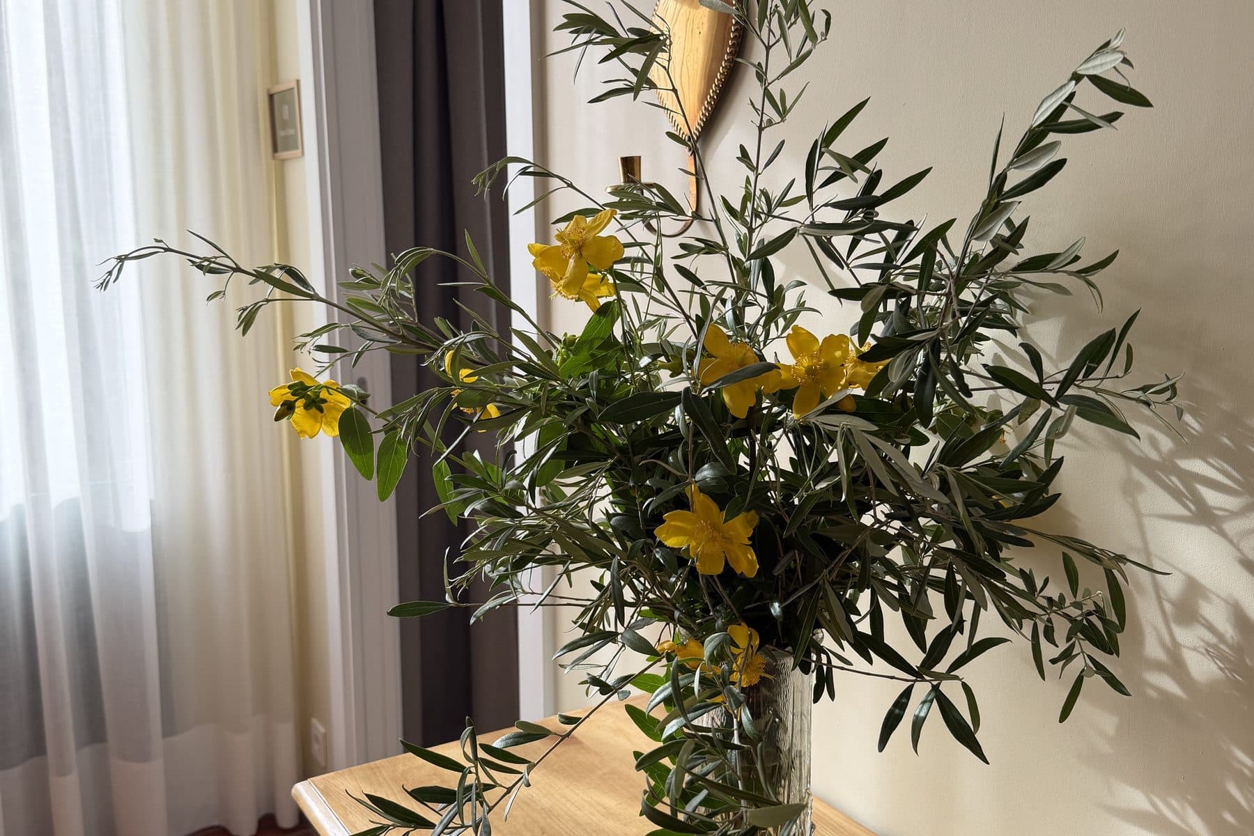Ramo de flores amarillas y ramas de olivo en un pasillo de la casa